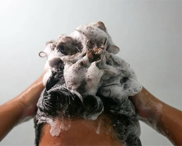 Person washing hair with shampoo 