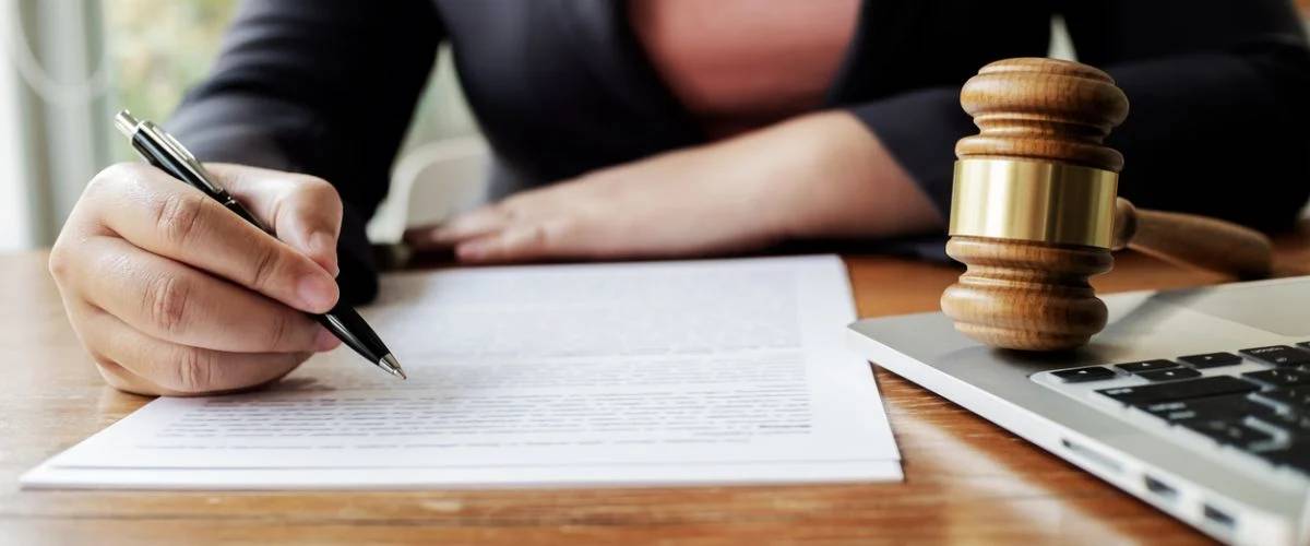 An image of a pen and paper with writing on it, symbolizing contracts